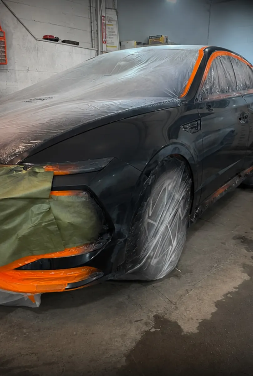 Black sedan with the front end masked for paint